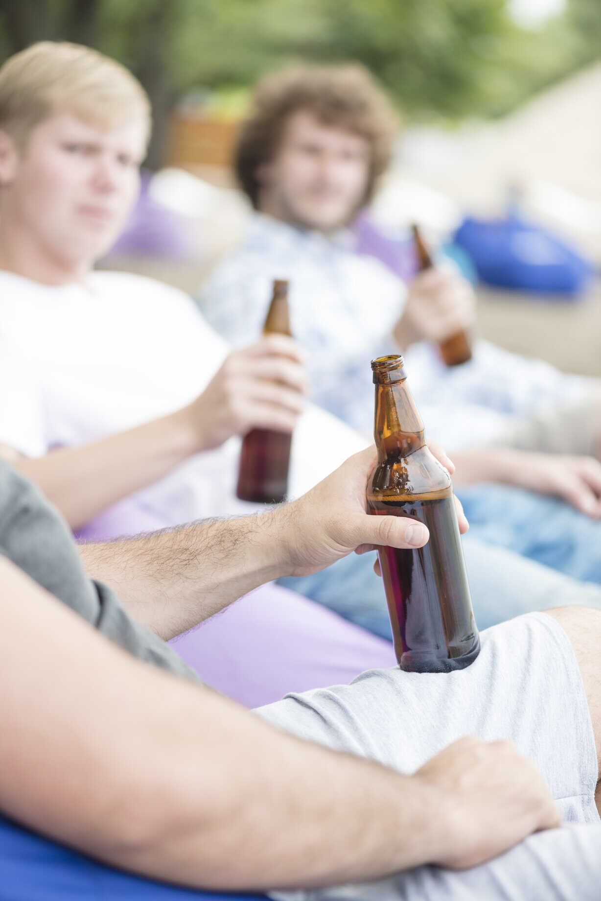 Des personnes tenant des bouteilles de bière lors d’un moment convivial en extérieur.
