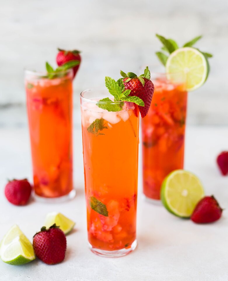 Verres de boissons garnis de fruits et de feuilles de menthe.