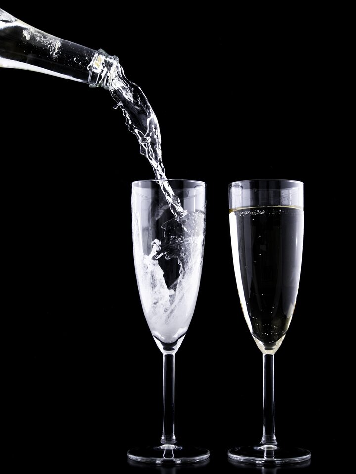 De l’eau versée dans une flûte sur un fond noir.